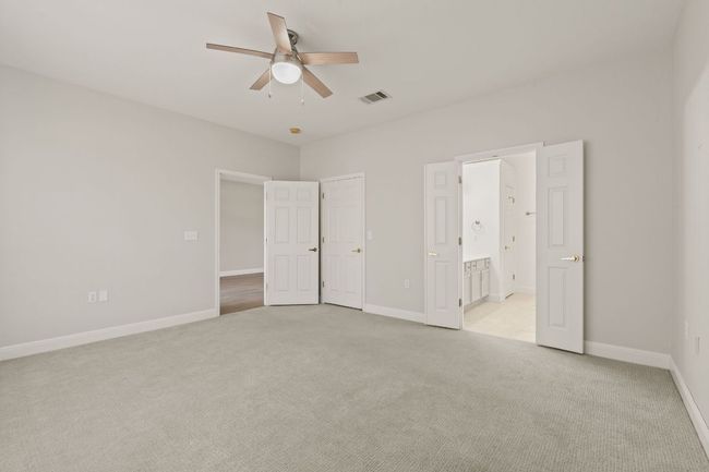 Unfurnished bedroom featuring baseboards, connected bathroom, visible vents, and light carpet | Image 20