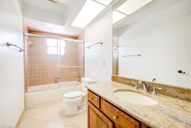 Bathroom with tile patterned floors, vanity, toilet, and enclosed tub / shower combo | Image 21