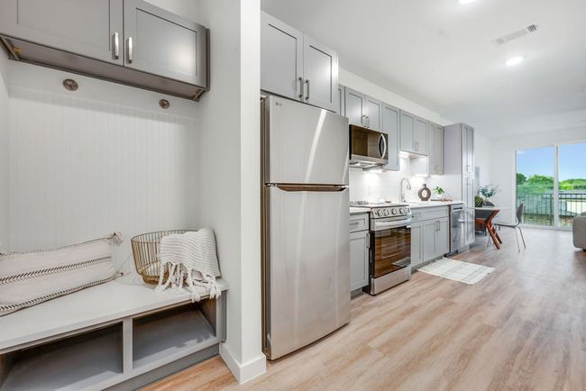 Kitchen with stainless steel appliances, gray cabinets, light wood-style flooring, decorative backsplash, and light countertops | Image 8