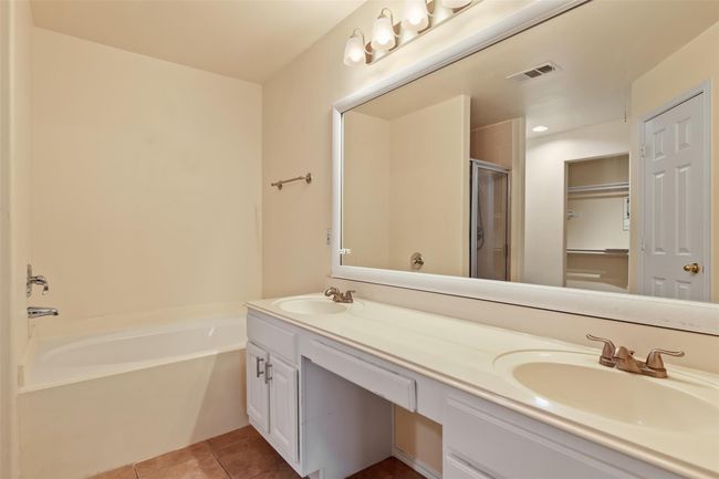 The primary bathroom has plenty of space with double sinks, framed mirror and a knee space vanity. It also features a large garden tub. | Image 15
