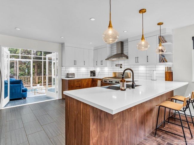 Huge chef's kitchen with 2025 new & updated cabinetry, gleaming white quartz counters, over the stove pot filler, gorgeous new backsplash, stainless steel appliances including fridge, dishwasher, 6 burner gas stove, wall oven, microwave & an apron sink. | Image 16