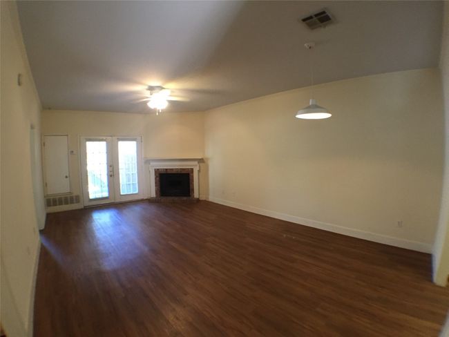 Unfurnished living room featuring dark wood-type flooring, visible vents, baseboards, and ceiling fan | Image 14