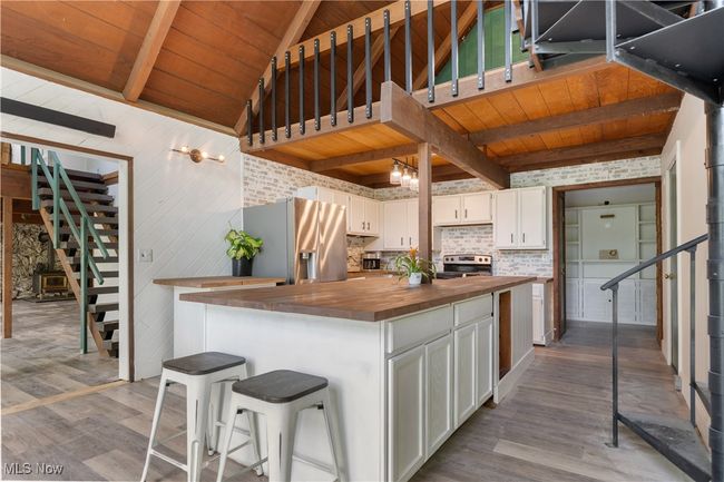 Kitchen featuring wooden counters, appliances with stainless steel finishes, dark wood-style flooring, wood ceiling, and white cabinets | Image 6