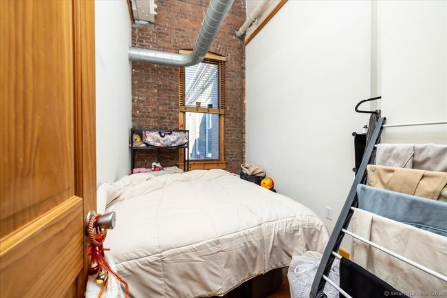 Bedroom with exposed brick walls, high ceilings, and large window that allows in tons of natural light | Image 13
