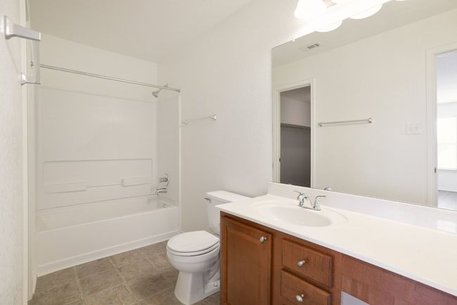 Bathroom featuring toilet, shower / washtub combination, visible vents, and vanity | Image 23