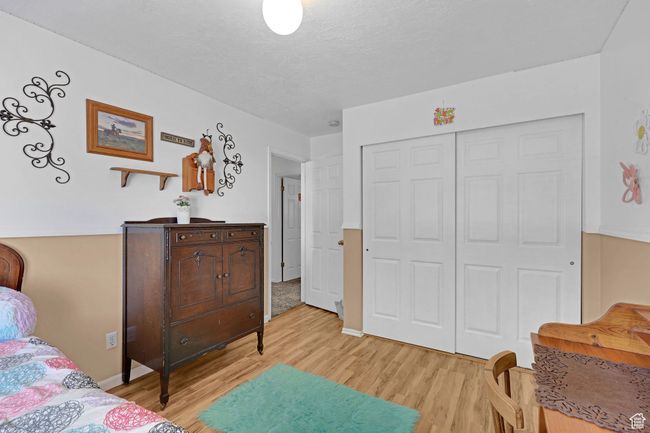 Bedroom with light wood-style floors, a closet, a textured ceiling, and baseboards | Image 19