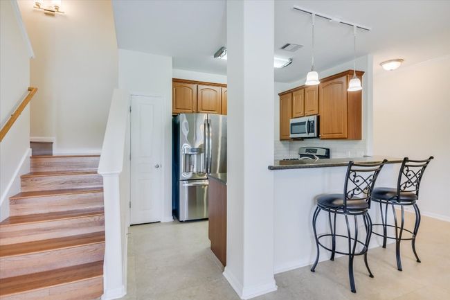 Kitchen with track lighting, appliances with stainless steel finishes, a breakfast bar area, brown cabinets, and tasteful backsplash | Image 7