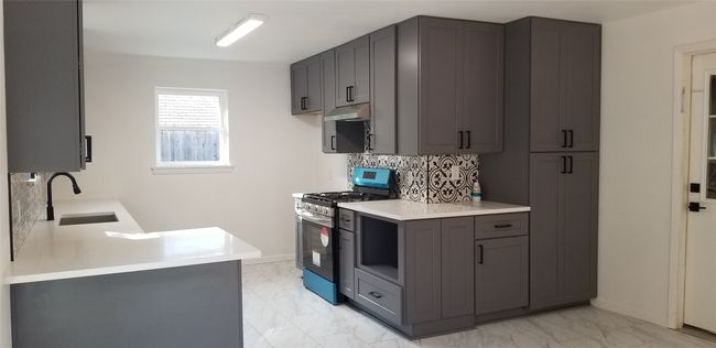 Kitchen with stainless steel gas range, a sink, light marble finish flooring, and backsplash | Image 12