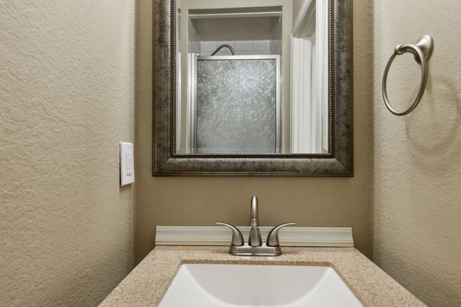 Full bathroom with an enclosed shower, vanity, and a textured wall | Image 23