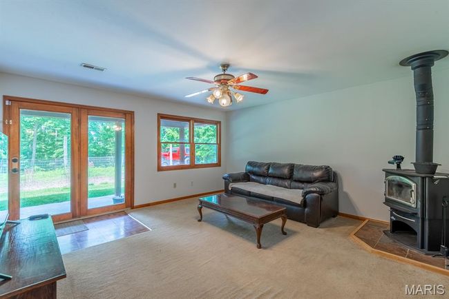 Carpeted living room with a wood stove and a ceiling fan | Image 4