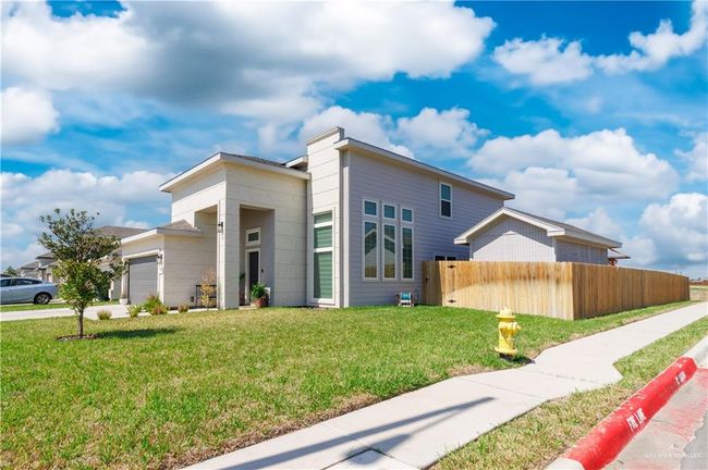 View of front facade featuring a garage, fence, driveway, and a front lawn | Image 17