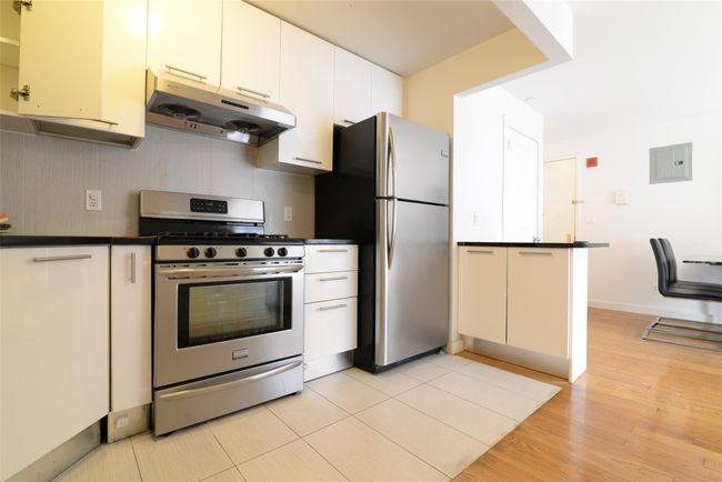 Kitchen with stainless steel appliances, extractor fan, dark countertops, and light wood-style flooring | Image 7
