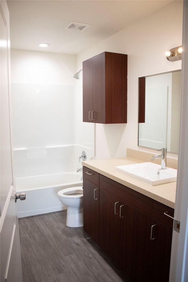 Bathroom featuring shower / tub combination, toilet, wood finished floors, vanity, and visible vents | Image 7