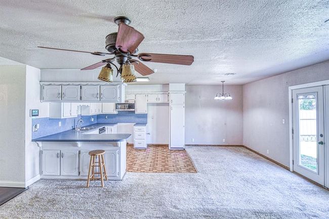 Kitchen featuring stainless steel microwave, a peninsula, a sink, a chandelier, and light colored carpet | Image 6