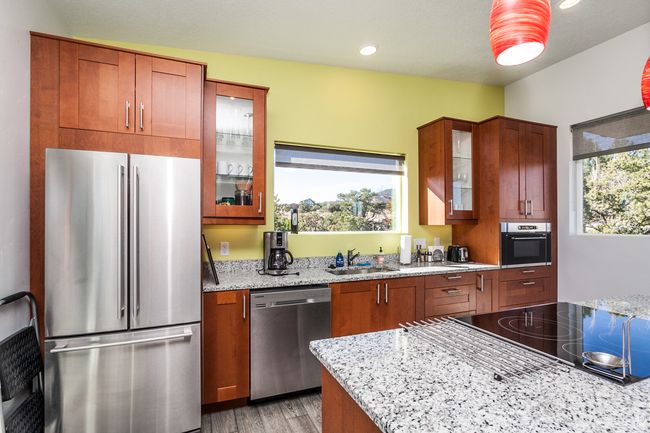 Kitchen with a wealth of natural light, light stone counters, a sink, and stainless steel appliances | Image 35