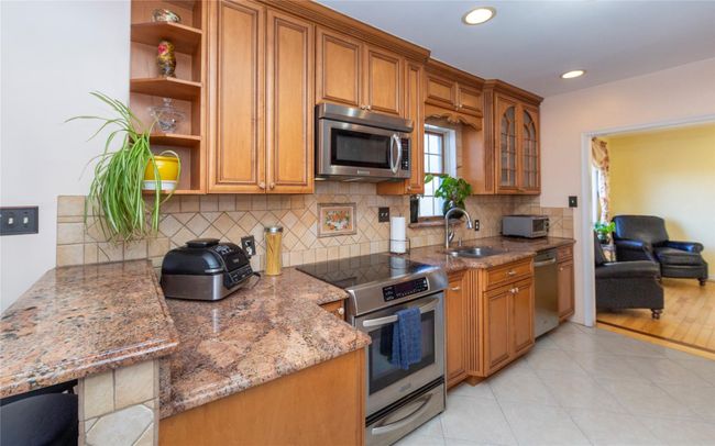 Kitchen with brown cabinets, a sink, open shelves, and stainless steel appliances | Image 23