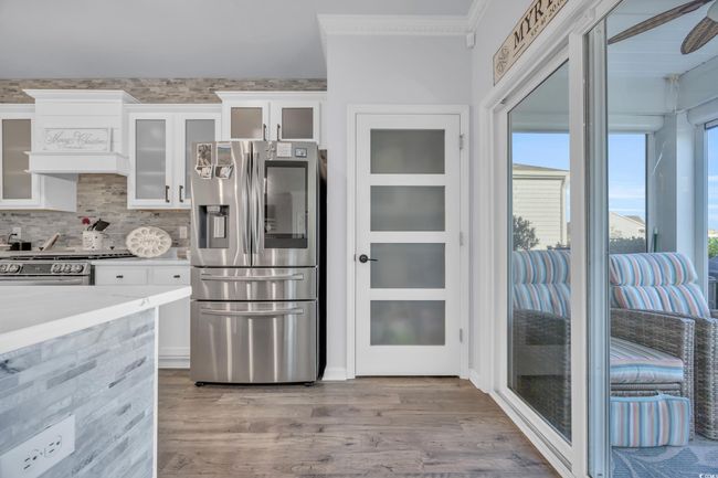 Kitchen featuring stainless steel appliances, crown molding, wood finished floors, white cabinetry, and light countertops | Image 16