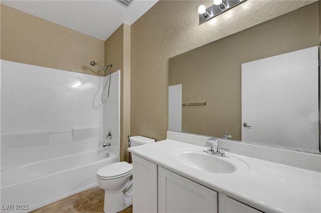 Bathroom with toilet, vanity, shower combination, visible vents, and a textured wall | Image 21