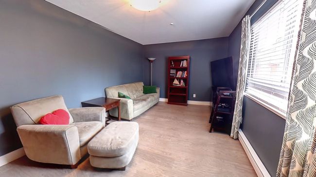 Living area featuring a baseboard heating unit, baseboards, and wood finished floors | Image 22