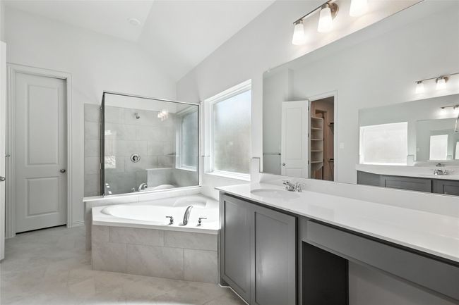 Bathroom featuring a bath, vaulted ceiling, vanity, tiled shower, and a walk in closet | Image 22