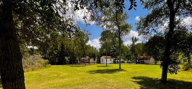 View of property's community featuring a lawn, a storage unit, and view of wooded area | Image 5