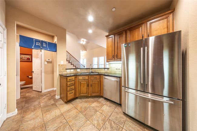 Kitchen featuring stainless steel appliances, brown cabinetry, backsplash, recessed lighting, and light stone finish flooring | Image 16
