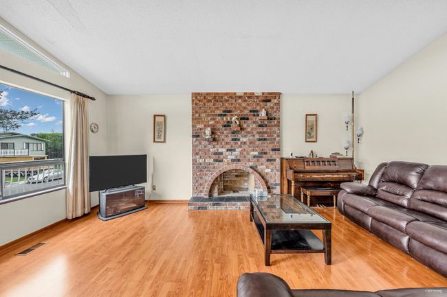 Living room with wood finished floors, lofted ceiling, and a brick fireplace | Image 9