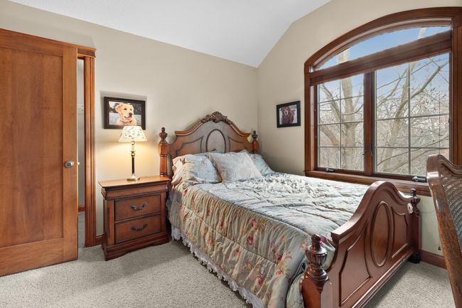 Upper-level second bedroom with view toward large windows and walk-in closet. | Image 37