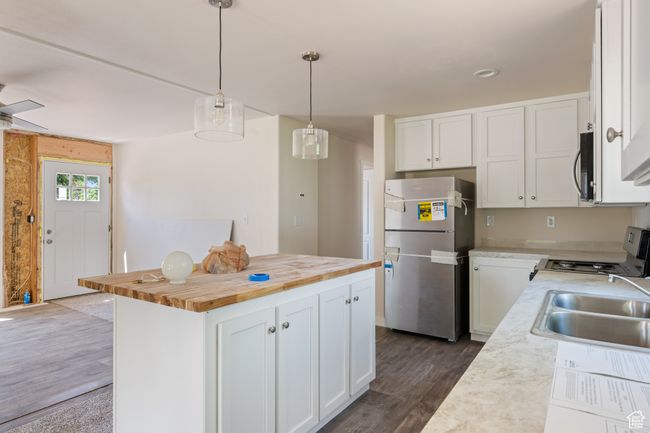 Kitchen featuring freestanding refrigerator, range, wooden counters, a sink, and dark wood-type flooring | Image 7