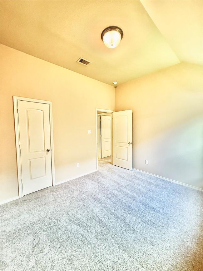 Second bedroom is a carpeted room with neutral walls and a simple ceiling light fixture. Bedroom ideal for a bedroom or office space. | Image 9