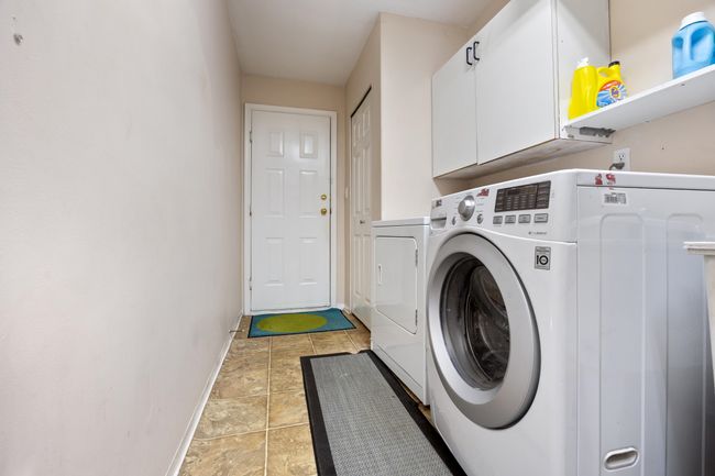 Laundry area featuring baseboards, cabinet space, stone finish floor, and washing machine and clothes dryer | Image 6