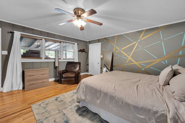 Bedroom featuring wood finished floors, a ceiling fan, and crown molding | Image 19