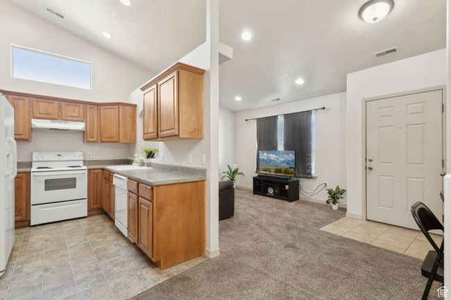 Kitchen with white appliances, under cabinet range hood, light countertops, light carpet, and recessed lighting | Image 14