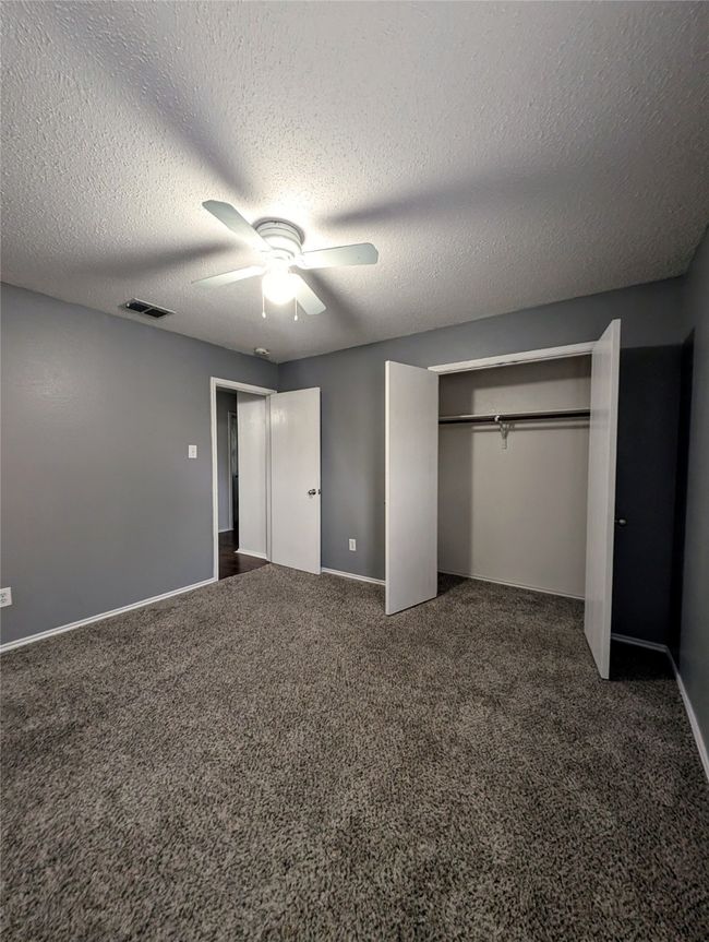 Unfurnished bedroom with carpet floors, a textured ceiling, a closet, baseboards, and ceiling fan | Image 14