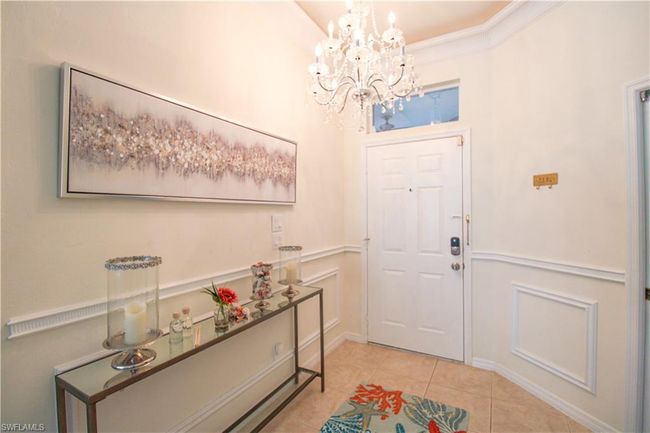 Entryway featuring ornamental molding, light tile floors, and an inviting chandelier | Image 16