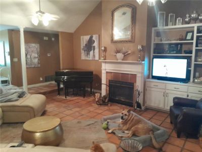 Living room with lofted ceiling, ceiling fan, a fireplace, and light tile patterned floors | Image 3