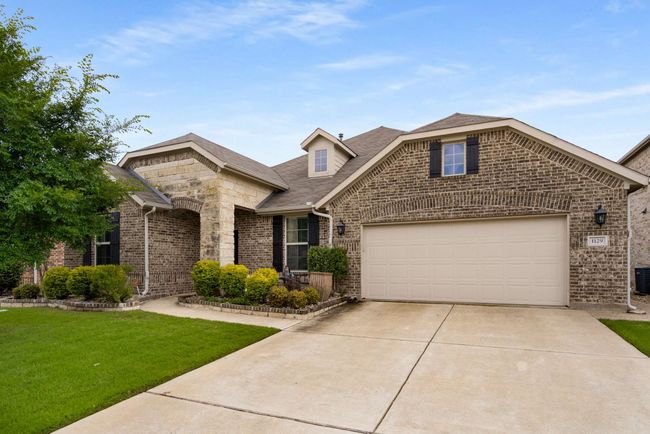 View of front facade with driveway, brick siding, a front lawn, central AC, and a garage | Image 27