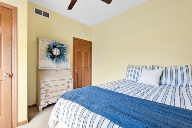 Spacious second bedroom with a large window for natural light and a modern, updated ceiling fan. | Image 22