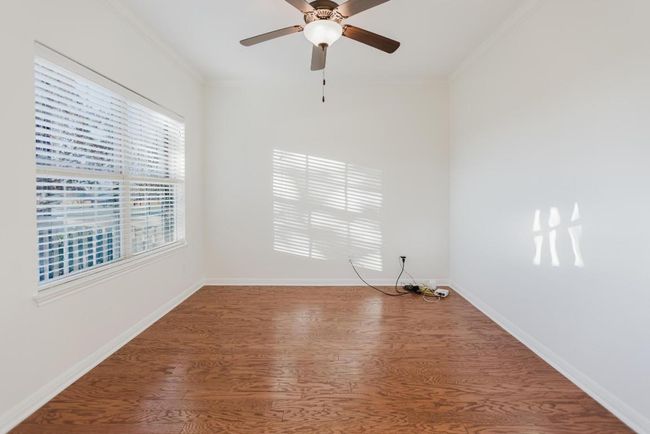 Empty room with ceiling fan, wood finished floors, baseboards, and ornamental molding | Image 7