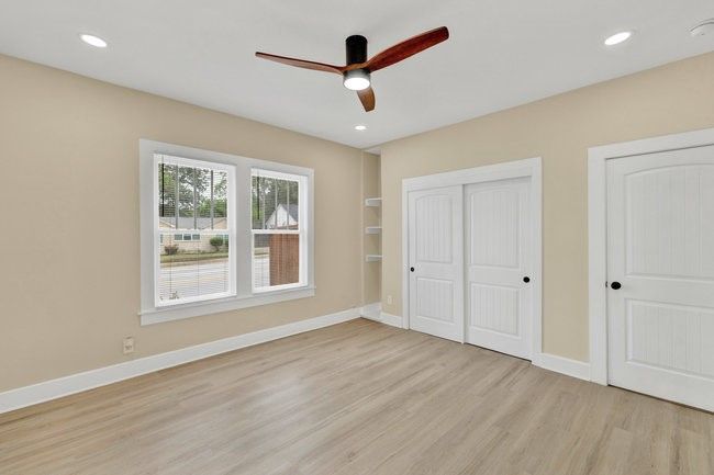 Unfurnished bedroom featuring a ceiling fan, baseboards, multiple closets, and light wood-style floors | Image 25