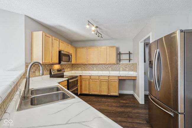 kitchen with stainless steel appliances, a sink, open shelves, a textured ceiling, and dark wood finished floors | Image 26