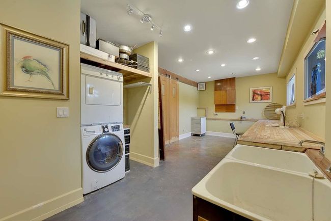 Washroom featuring stacked washer / drying machine, a barn door, and recessed lighting | Image 23