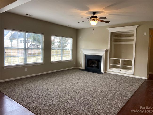 Great room with great light from row of windows, gas fireplace and inset wall shelves. | Image 10