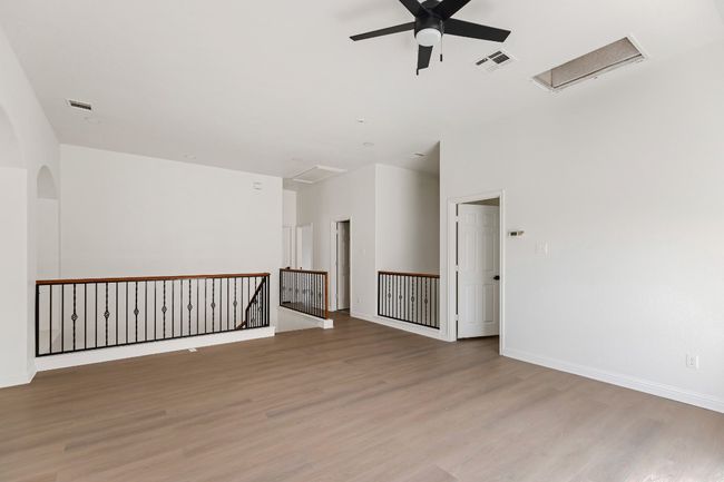 Empty room with a ceiling fan, light wood-style floors, attic access, and arched walkways | Image 26