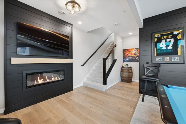 Entry-level entertaining space with two mounted TVs on sleek black slat walls, creating a modern and functional vibe. This versatile room could also serve as a cozy family den or a productive home office—perfectly adaptable to fit your needs. | Image 15