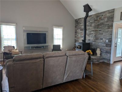 Living room featuring dark hardwood / wood-style flooring, a wood stove, and high vaulted ceiling | Image 3