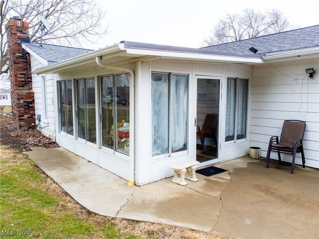 View of side of property featuring a shingled roof, a patio, and a chimney | Image 7