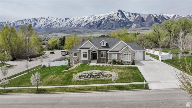 View of front facade with stone siding, a front yard, concrete driveway, and fence | Image 5