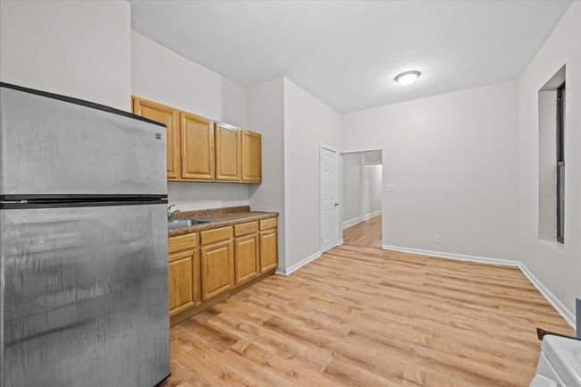 Kitchen with freestanding refrigerator, light wood finished floors, and dark countertops | Image 12