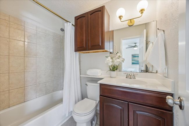 Bathroom with vanity, shower / tub combo, a textured ceiling, and ceiling fan | Image 18